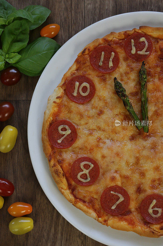 这是一个自制的披萨时钟，上面有意大利辣香肠切片、马苏里拉奶酪和芦笋作为时钟指针，告诉时间23:00 11点。这是意大利披萨餐厅为孩子们的生日派对食物而制作的儿童披萨时钟